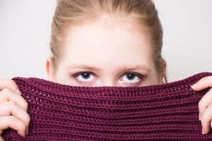 woman hiding her face behind sweater