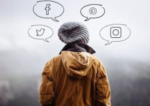 person photographed from the back with speech bubbles containing icons for Facebook, Twitter, Pinterest, and Instagram