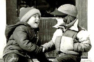 old timey photo of two children in winter wear shaking hands