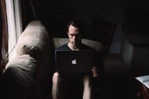 writer typing in a Macbook in the dark