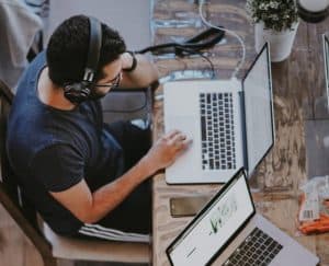 man wearing headphones and working on online training on macbook