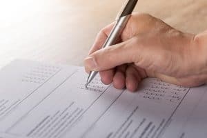 hand holding a pen checking off survey form