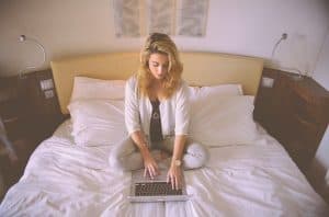 woman sitting in bed using laptop