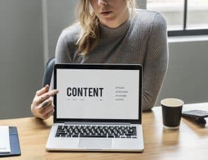 woman holding up laptop with the word "content" displayed