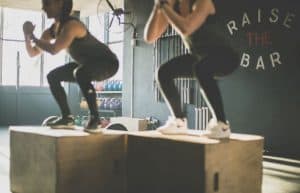 two women doing squats on benches in a gym