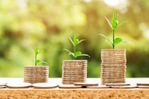 three stacks of coins with different heights, with plants on top with different heights