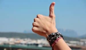 shot of hand doing a thumbs-up sign with bracelets on the wrist